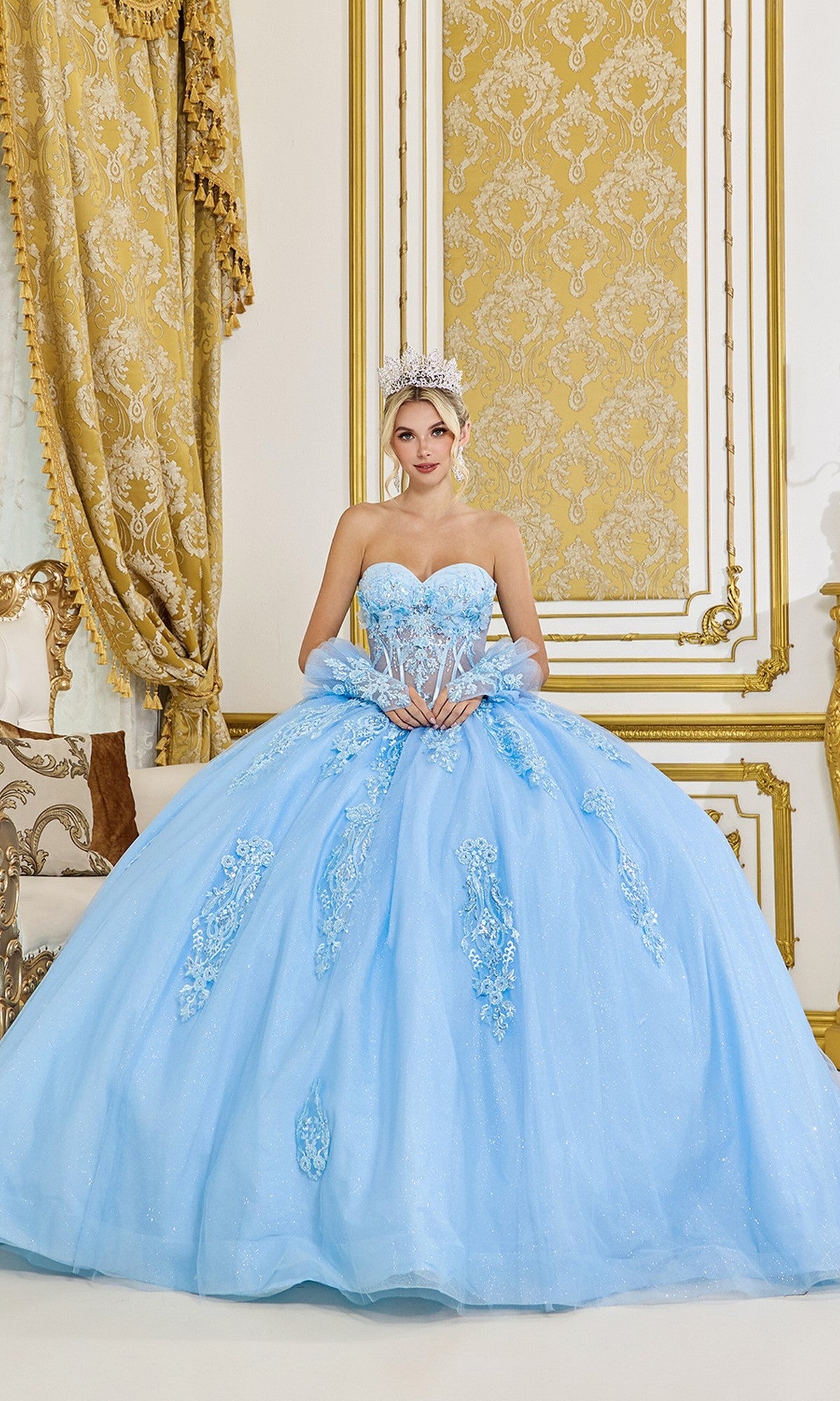 A woman in the Bahama Blue Quinceanera Dress 5091 by Dancing Queen and a tiara poses in an ornate gold and white room.